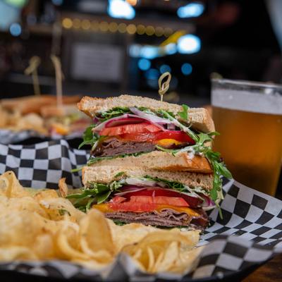 Roast beef sandwich, with cheddar, arugula, radish, onion, tomato, horseradish, and chips.