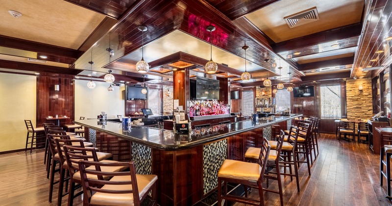 Interior of a modern bar, wooden bar stools, pendant lighting, and stone accent walls