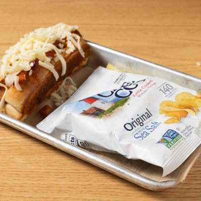 Beef Chili Cheese Dog served with a bag of potato chips.