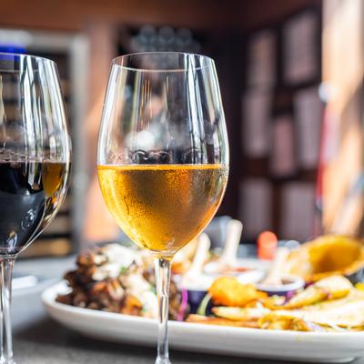 Two glasses of wine -- one red, one amber -- in the foreground, in front of a colorful dish of Georgian vegetables