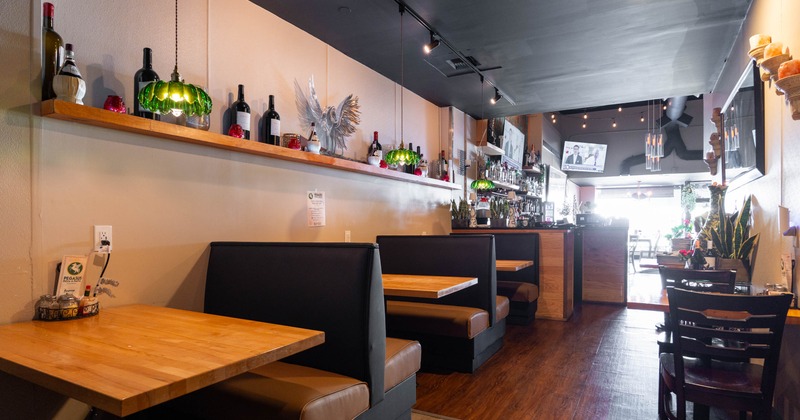 Interior, dining area, seating booths with wooden top tables, bar and entrance in the back