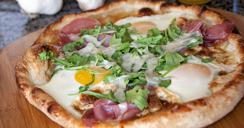 Pizza with eggs, argula and ham