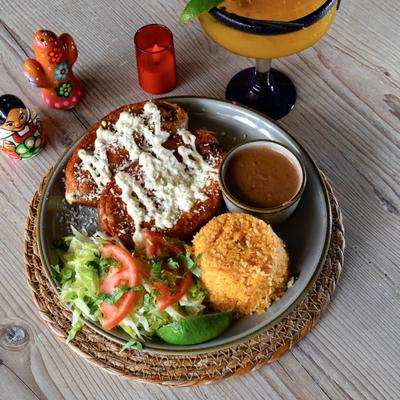 Stuffed poblano peppers with red salsa, sour cream, cheese, rice, beans, and salad.