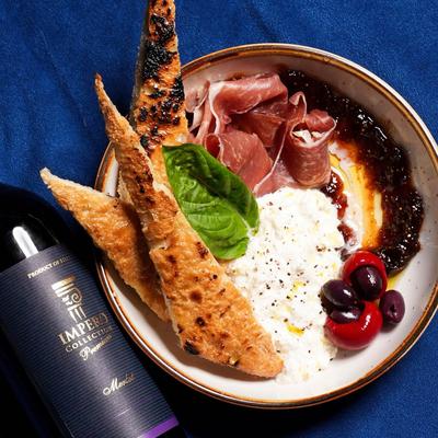 Prosciutto and Brie Cheese Spread and a bottle of wine, flat lay view.