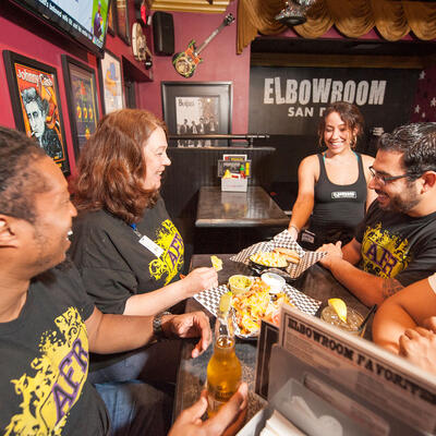 Staff member serving food and drinks for four guests