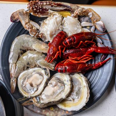Platter of raw seafood featuring oysters, crayfish, and shrimp.