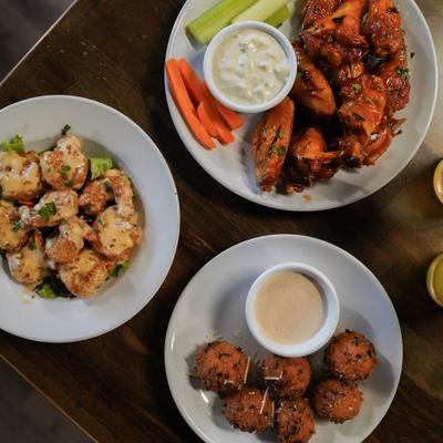 Buffalo wings with celery, carrots, and ranch alongside sauced shrimp and fried bites.