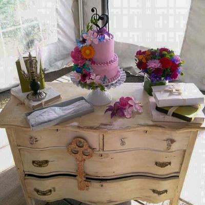 Elegant setup on a rustic dresser featuring a pink cake and various decorative items.