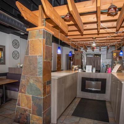 Restaurant interior with wood beams, stone pillars, and booth seating.