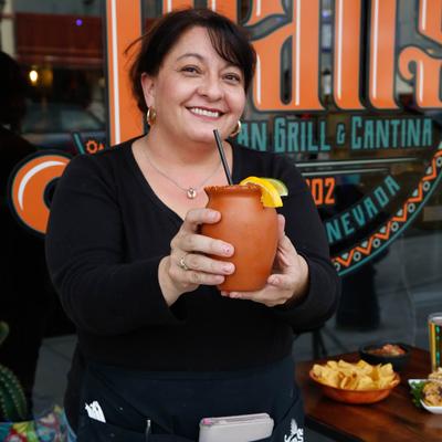 Bartender serving a Paloma cocktail in a clay cup.