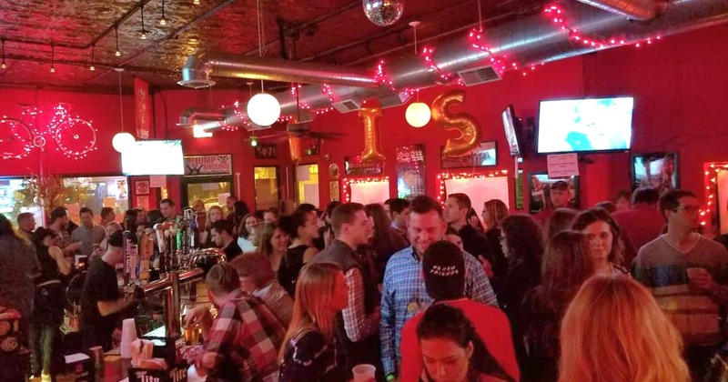 People socializing in a crowded bar under red lights