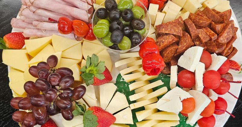 A colorful charcuterie board featuring assorted cheeses, meats, fruits, and olives