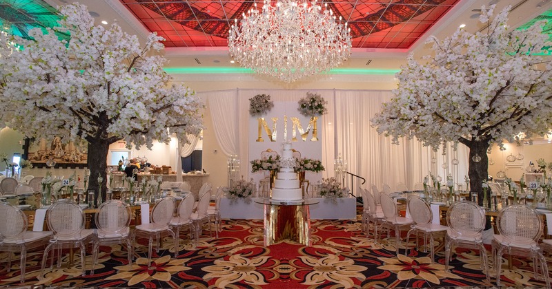 Luxurious event setting with cherry blossom trees, a crystal chandelier and a multi-tiered cake