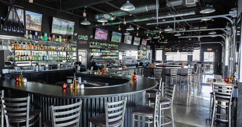 Interior view of a modern bar - a curved counter, stocked shelves and sports TVs