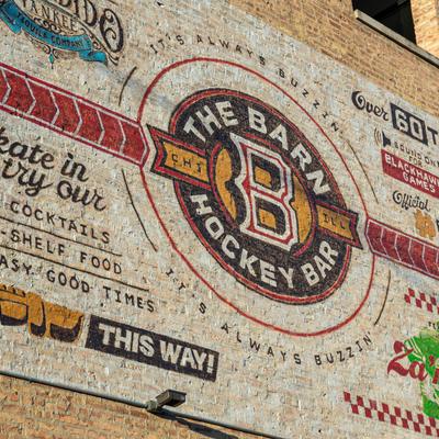 The Barn Hockey Bar mural signage on a brick building wall.