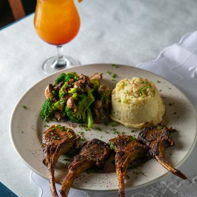 Rack of lamb served with a side of mashed potatoes and sauteed broccoli and mushrooms.