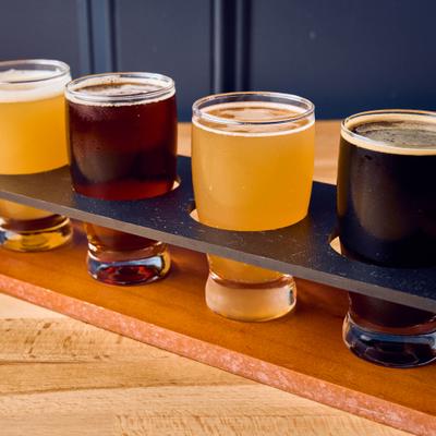 Beer tasting flight featuring four distinct pours served on a wooden tray.