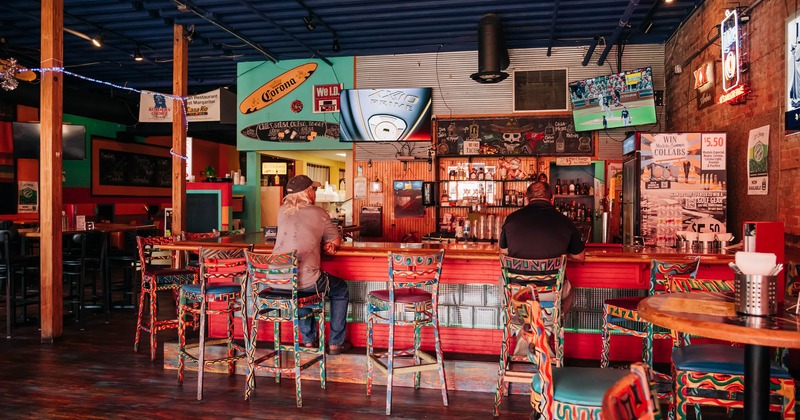 A bar, chairs, drink rack behind, guest seating