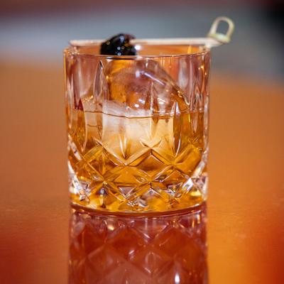 Old fashioned cocktail garnished with cherry on a pick.