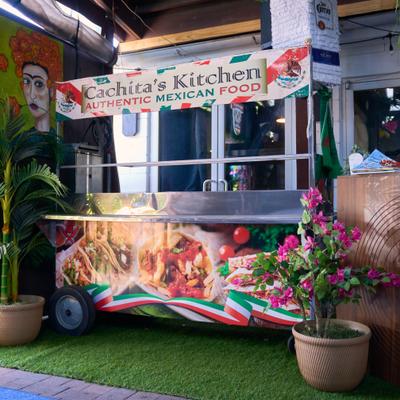 Cachita's Kitchen food cart with colorful decor and potted flowers.
