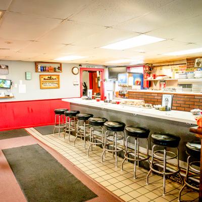 Interior of a diner with a long counter and black cushioned stools.