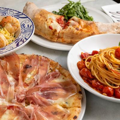Two different types of pasta served alongside pizza and calzone.