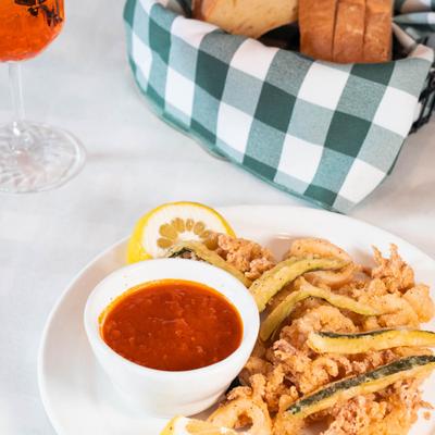 Fried calamari and zucchini served with marinara sauce, bread, and a drink.