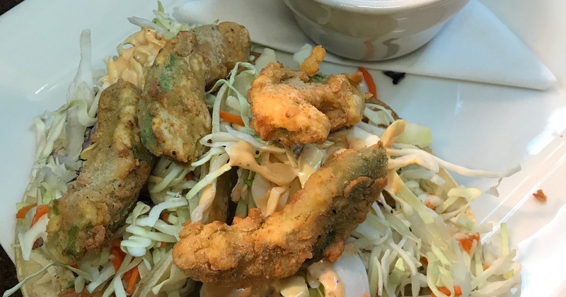 Fried fish tacos, served with a side of a sauce