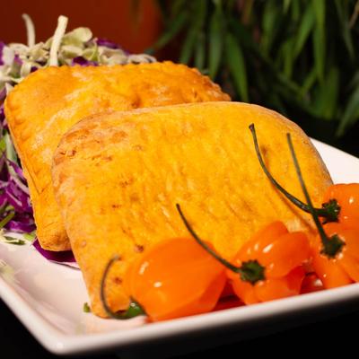 Two beef empanadas on a plate with red cabbage salad and habanero peppers.