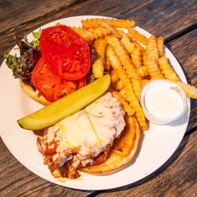 Fried chicken sandwich, with cheese, lettuce, tomato, pickle, and fries.