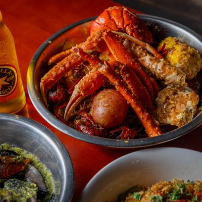 A bowl of seafood with crab legs, crawfish, and corn on the cob.