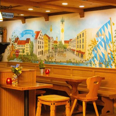 Interior, dining area, wooden corner banquette bench with wooden table, over the wall mural.