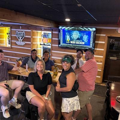 Group of friends smiling and sitting around a bar table with drinks.