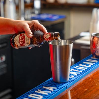 A hand pouring beer into a cocktail tin.