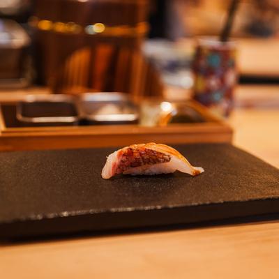 Seared nigiri sushi on a black serving plate.