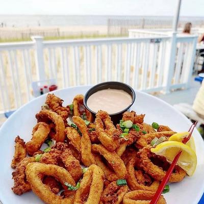 Fried calamari served with dipping sauce and a lemon wedge.