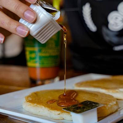 Maple syrup being poured over pancakes