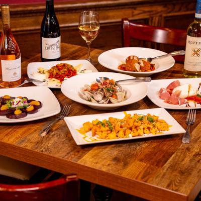 Assorted appetizer plates on a wooden table with wine.