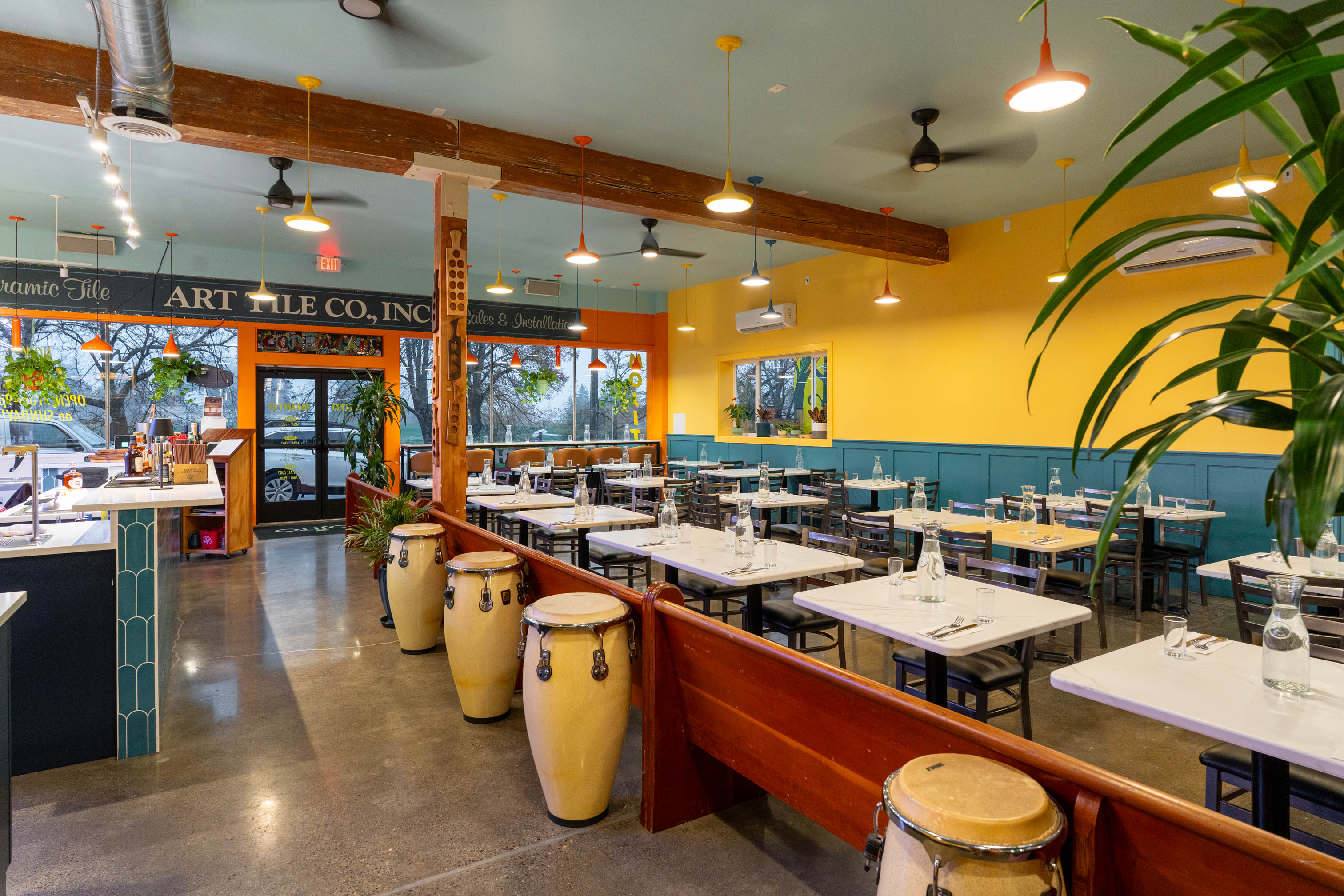Dining area's interior with large potted plants and several conga drums