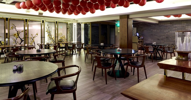 Inside, dining area with round black tables, wooden chairs, and red paper lanterns on the ceiling