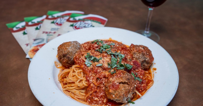 Spaghetti topped with meatballs, tomato sauce, and fresh herbs