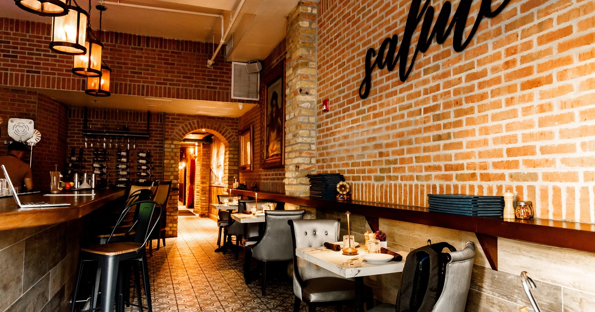 Modern style of interior design with a bar and set dining tables along the brick wall
