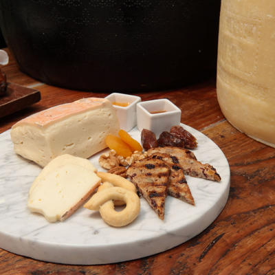 Assorted cheese types, bread, and condiments served on a board