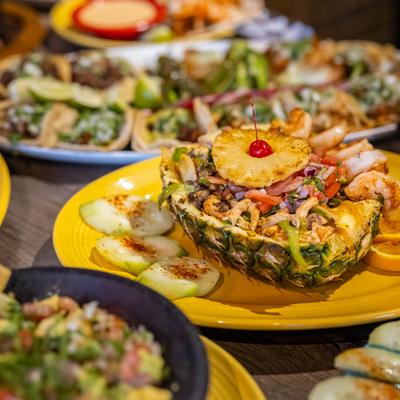 Pineapple shrimp bowl on a table with tacos.