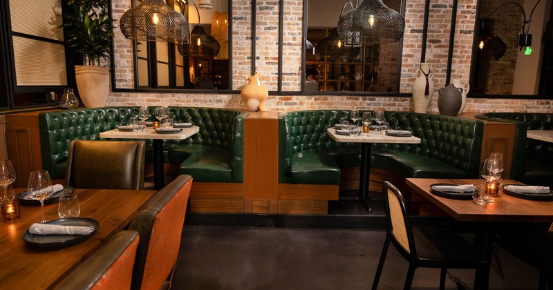 A high back leather booth with glasses and tableware on the table