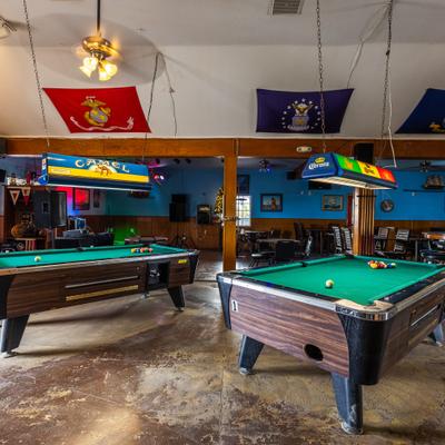 Interior with two pool tables and a seating area visible in the background..
