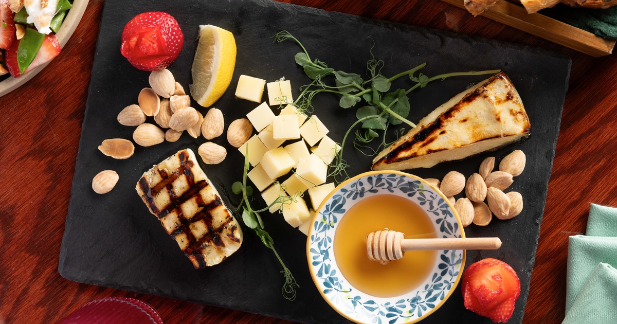 Grilled cheese board with honey, almonds, strawberries, lemon, and cubed cheeses