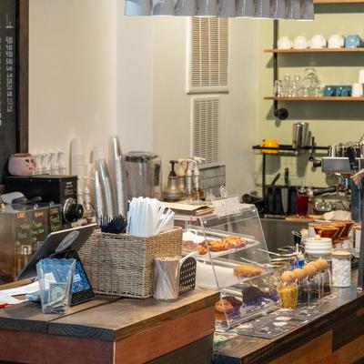 Service counter featuring pastry in a display case, glassware, and a coffee machine.