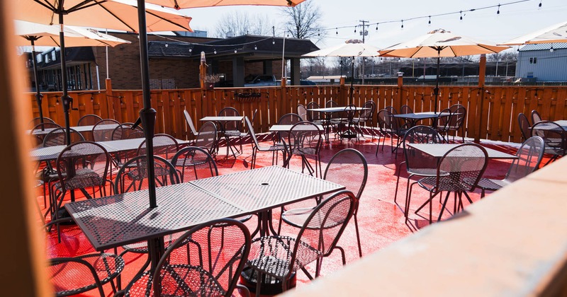 Exterior, outdoor seating area, metal tables with chairs, concrete flooring, wooden railing