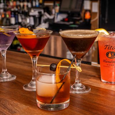 Assorted cocktails on a wooden bar counter.
